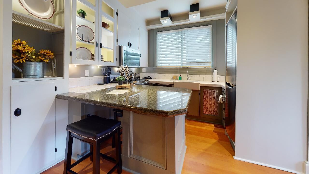 A modern kitchen with a granite countertop, white cabinetry, and a built-in island with bar stools.