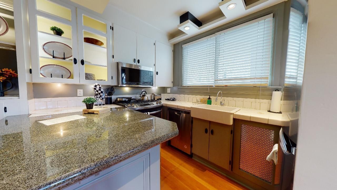 A modern kitchen with granite countertops, stainless steel appliances, and white cabinetry.
