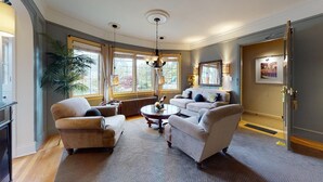A spacious living room with a large window, a chandelier, and a fireplace. - Lower Suite: a classic suite in a quiet Seattle home (Seattle)