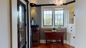 A room with a wooden floor, a window with a view, a table with a vase and a plant, and a white cabinet with drawers. - Lower Suite: a classic suite in a quiet Seattle home (Seattle)