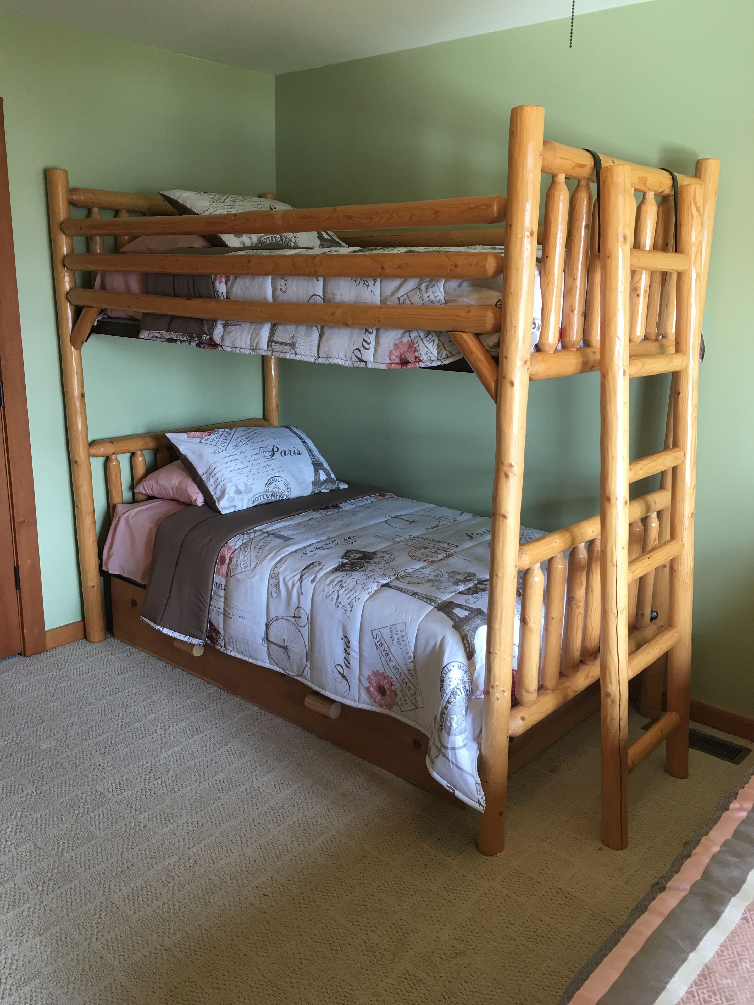 A bunk bed with a wooden frame and a Paris-themed bedspread.