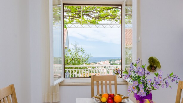 A balcony with a view of the sea, a table with a bowl of fruit, and a vase with flowers. - Rooms Rita - Double Room with Private Bathroom (No. 2) (Dubrovnik)