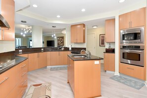 Una cocina moderna con electrodomésticos integrados, una isla central y vistas al salón.