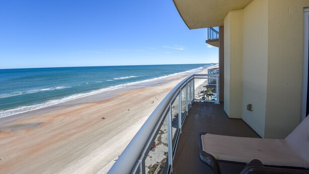 Un balcon avec vue sur une plage et l’océan.
