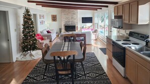 Een moderne keuken met een grote kookplaat, houten kastjes, en een eethoek met een tafel en stoelen.