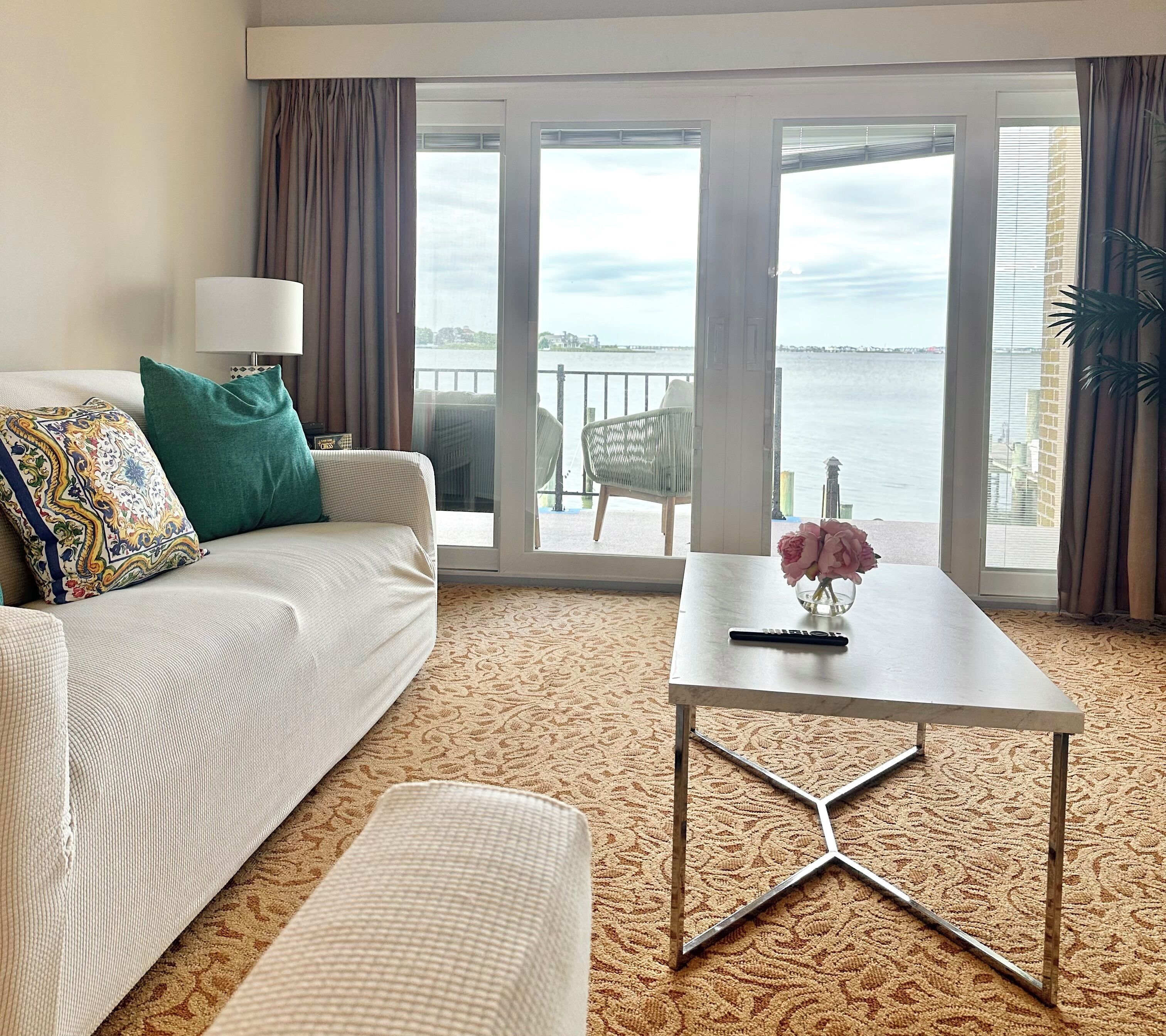 Ein Hotelzimmer mit Sofa, Couchtisch und Blick auf das Wasser.