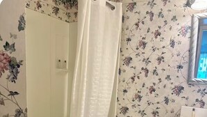 Et badeværelse med brusebad, toilet og håndvask.