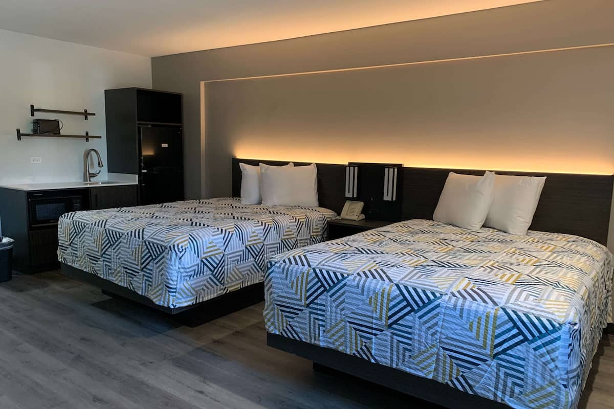 Ett hotellrum med två sängar, ett litet pentry och ett nattduksbord med en telefon.