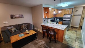 Een knus leefruimte met een kitchenette, een bank en een salontafel.