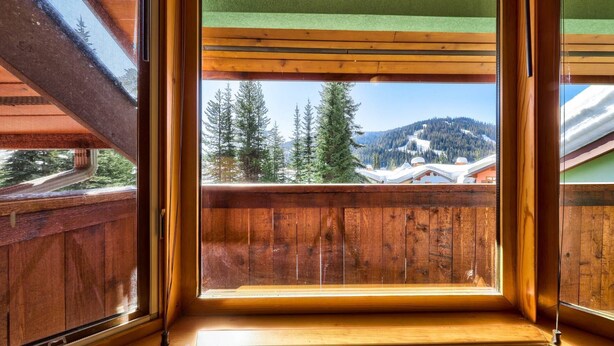 Een houten balkon met uitzicht op een besneeuwd berglandschap.