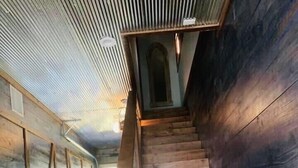 A wooden staircase with a herringbone floor pattern leading to an arched doorway. - Livin on the Edge on the Caddo River (Glenwood)