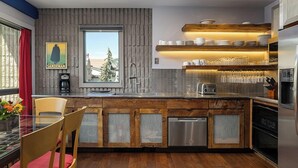 A modern kitchen with wooden cabinets, a built-in dishwasher, and a window with a view of trees. - Vail21 601 - 3 Bedroom Gold (Vail)