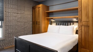 A bedroom with a bed, wooden headboard, built-in shelves, and a stone-patterned wall. - Vail21 601 - 3 Bedroom Gold (Vail)