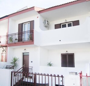 Un edificio de dos pisos con balcón, escalera y puerta.
