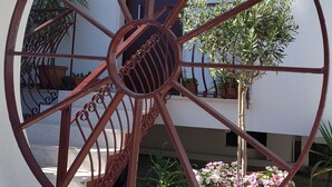 Vista a través de una ventana circular con estructura metálica, plantas en macetas y una puerta al fondo.