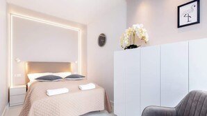 Een moderne slaapkamer met een bed, nachtkastjes, een kledingkast en een stoel.