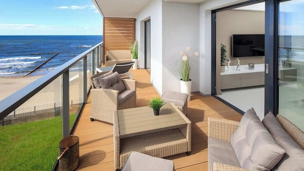 Een balkon met rieten meubels, een klein tafeltje en een bloempot.