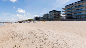 Een strand met meerlaags gebouwen, zandstrand en heldere lucht.