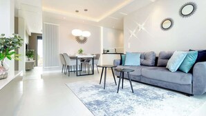 Een moderne woonkamer met een grijze bank, een salontafel en een eethoek met stoelen.
