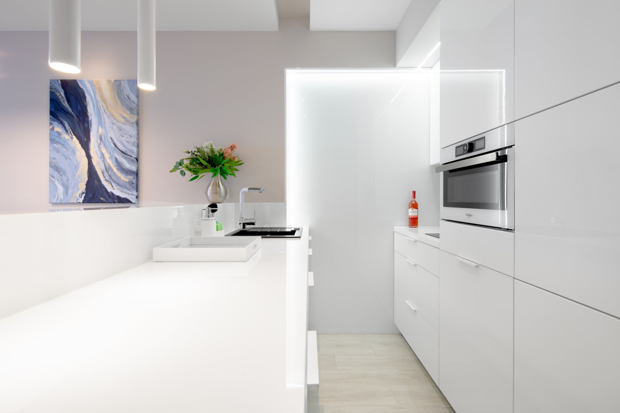 A modern kitchen with white cabinetry, a stainless steel oven, and a minimalist design.