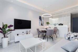 Un salon moderne avec un canapé blanc, une table à manger et un téléviseur à écran plat.