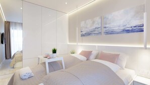 Una habitación de hotel moderna con una cama grande, una mesita de noche con una planta y una obra de arte en la pared.