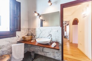 Une salle de bain avec un lavabo en marbre, un meuble-lavabo en bois et un grand miroir.
