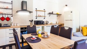 Uma cozinha moderna com mesa de jantar, cadeiras, cafeteira e micro-ondas.