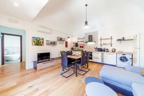 A modern apartment with a dining area, kitchen, and a large window.