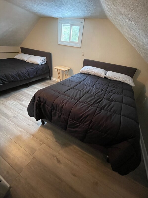A room with two beds, a small table, and a window.