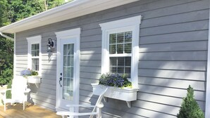 A house with a porch, two windows with flower boxes, and a white chair. - One bedroom fully equipped Mahone Bay luxury cottage (Mahone Bay)
