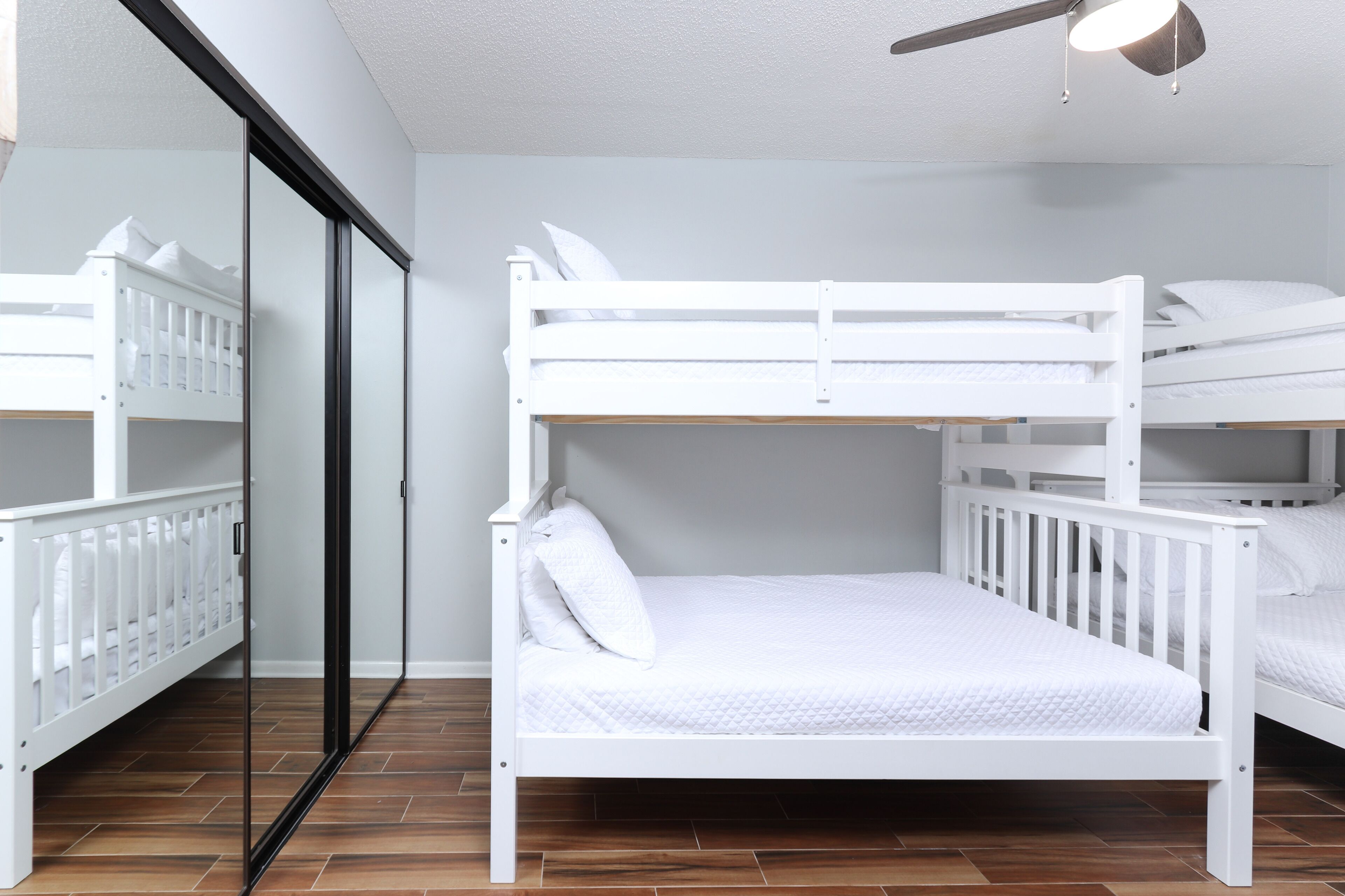 Une chambre avec un lit superposé, une porte coulissante et un ventilateur de plafond.