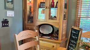 Ein Holzespeisesaal mit Stühlen, ein Schrank mit Glastüren und ein Kreidetafel-Schild.