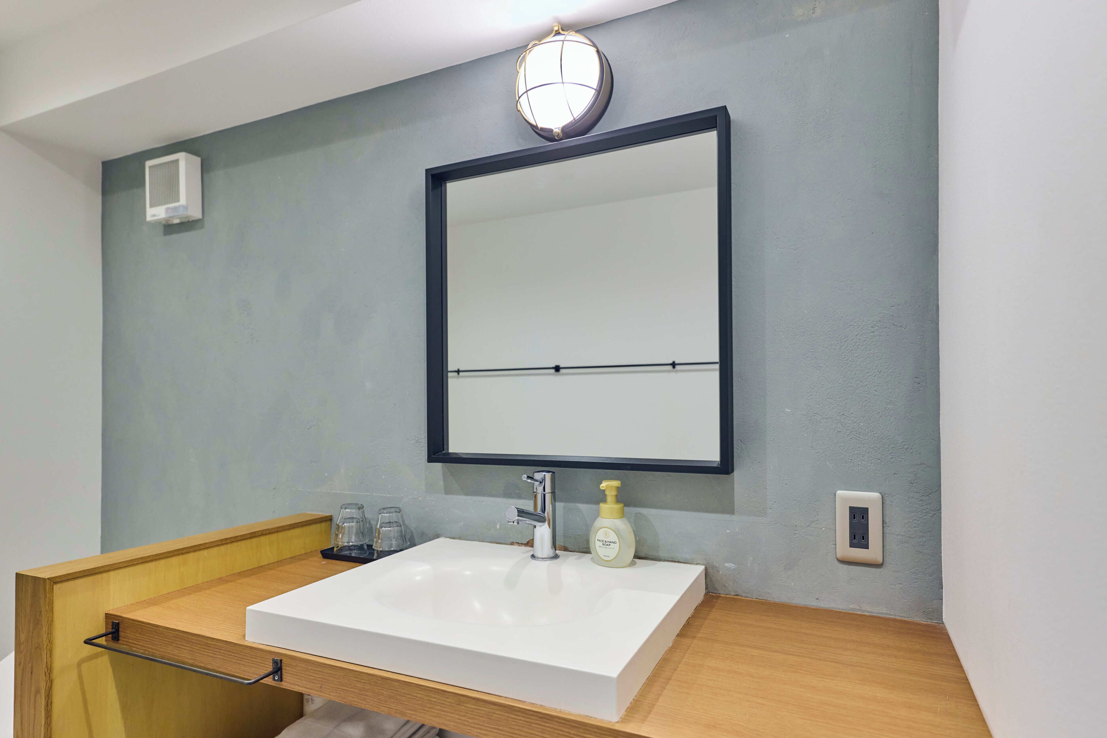 A bathroom with a white sink, a mirror, a towel rack, and a light fixture above the mirror.