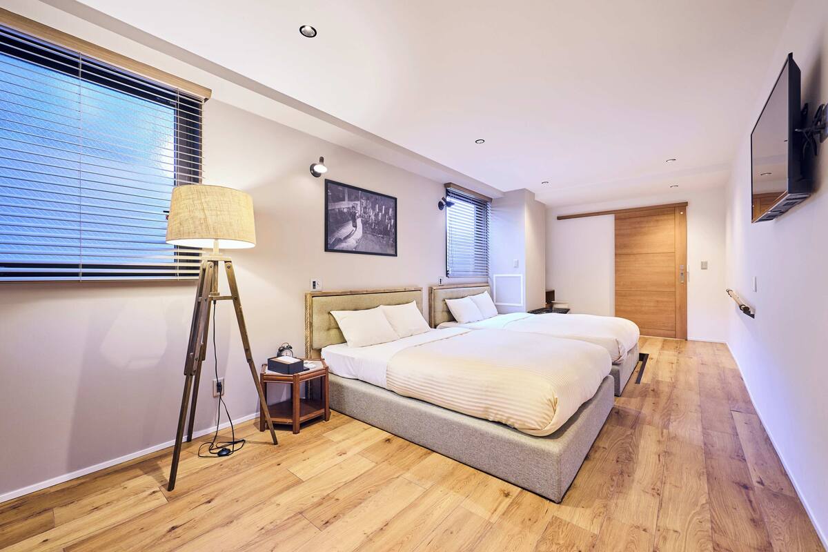Een moderne slaapkamer met een groot bed, een staande lamp, een lijst met een afbeelding en een houten deur.