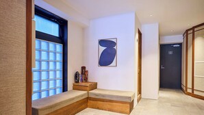 A modern hotel room with a built-in bench seating area, a large window with a view, and a minimalist wall art piece.