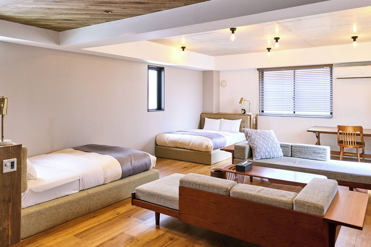 Een moderne, goed verlichte kamer met een houten plafond, een bed, een sofa, een klein tafeltje en een stoel.