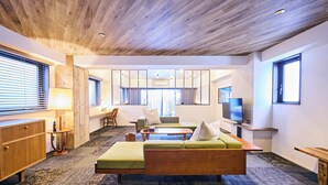 A modern living room with a wooden ceiling, a green sofa, a wooden coffee table, and a television on a stand.