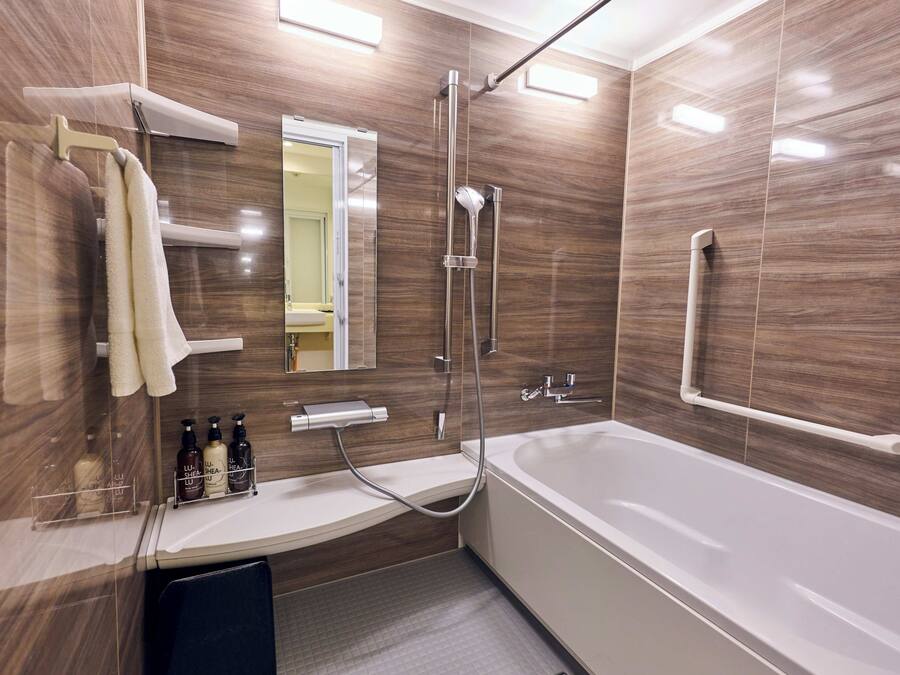 Une salle de bain moderne dotée d’une grande baignoire, d’une douche et d’un meuble-lavabo avec des articles de toilette.