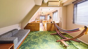 A modern loft bedroom with a green carpet, wooden headboard, and a hammock.