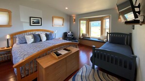 A bedroom with a large bed, a smaller bed, a desk, a chair, a TV mounted on the wall, and a window with a view of the outside. - The Waves House! Breathtaking Ocean View, Hot Tub, King Beds, Dog-Friendly. (Waldport)