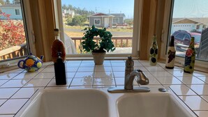 A kitchen with two sinks, a potted plant, and decorative bottles. - The Waves House! Breathtaking Ocean View, Hot Tub, King Beds, Dog-Friendly. (Waldport)