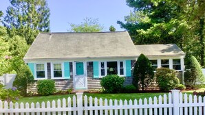 A two-story house with a white picket fence, a front porch, and a mailbox. - Cape Cod Beach Cottage, only 5 minute walk to Glendon beach & local restaurants (Dennis)
