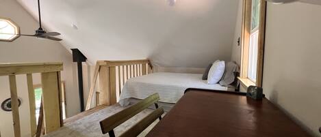 Een knusse, kleine kamer met een bed, een houten bank en een tafel.