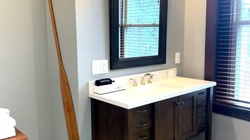 A bathroom with a dark wooden vanity, a white sink, and a mirror with three lights.