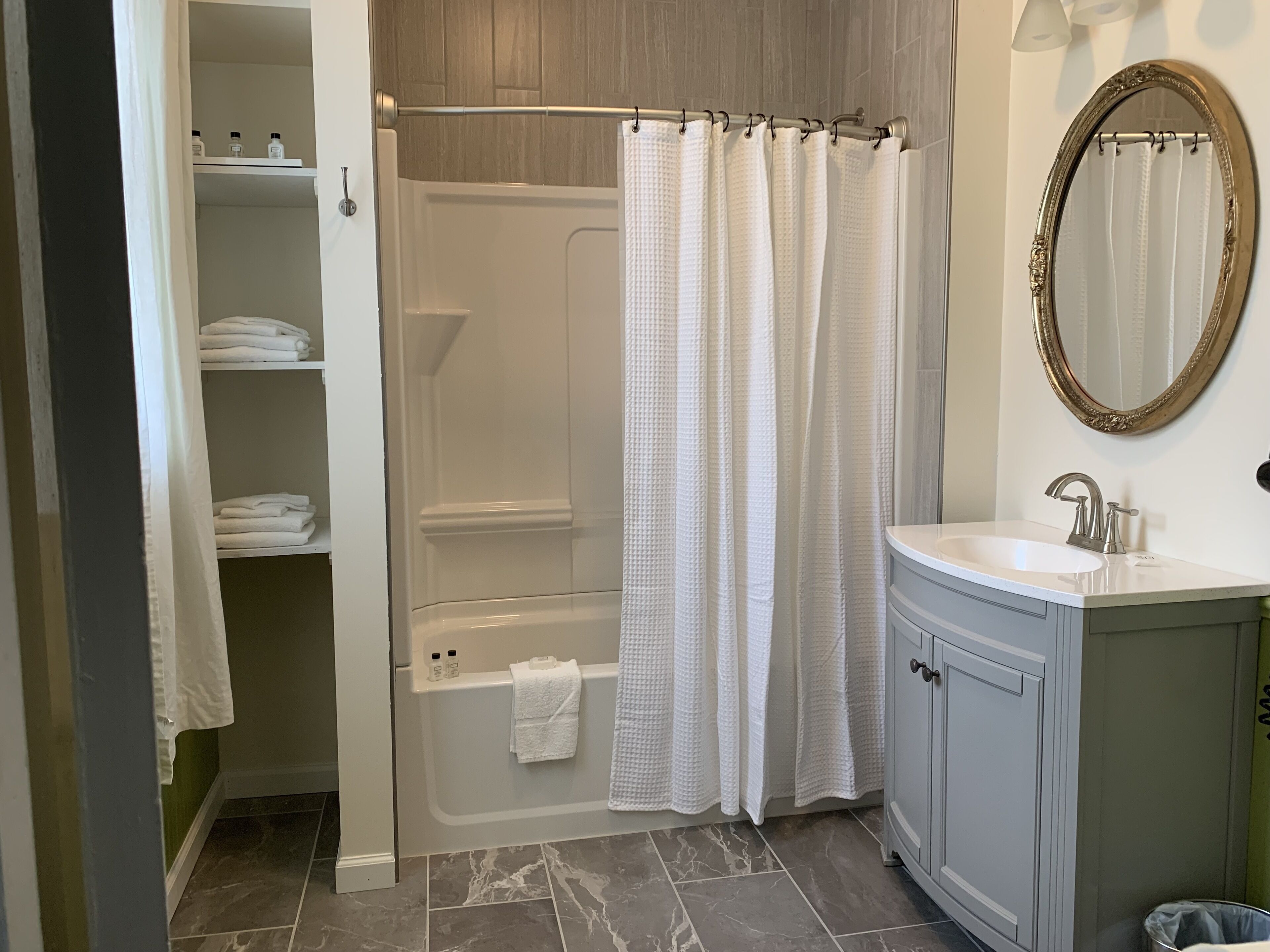 A bathroom with a bathtub, a shower, a vanity with a sink, and a mirror.