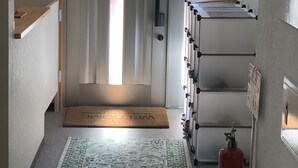 Un pasillo con una puerta, un extintor y un felpudo en la entrada.