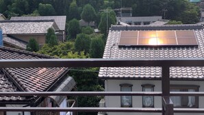 Zona residencial con techos de tejas tradicionales, algunos con paneles solares, y abundante vegetación en el fondo.