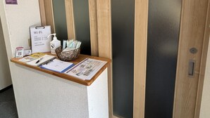 Un mostrador de recepción con un letrero que indica disponibilidad de Wi-Fi, una cesta con objetos y una puerta con paneles de vidrio esmerilado.