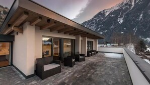 Un bâtiment moderne doté d’un toit plat, de grandes fenêtres et d’un espace extérieur aménagé pour s’asseoir.